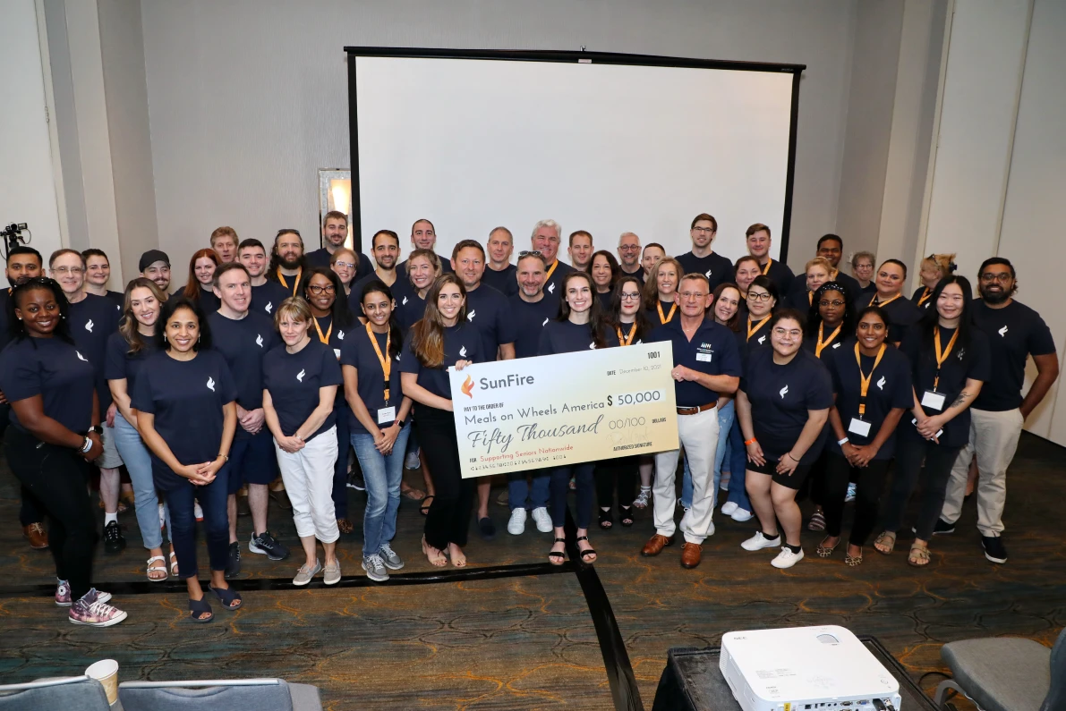 Photograph of SunFire employees holding a large donation check during company retreat