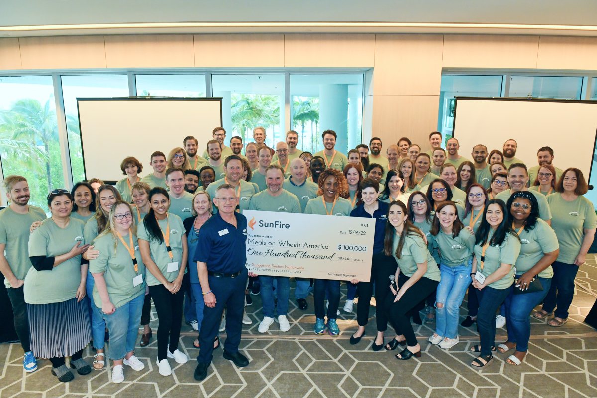 SunFire employees and Meals on Wheels America representatives pose with a giant donation check during a company retreat